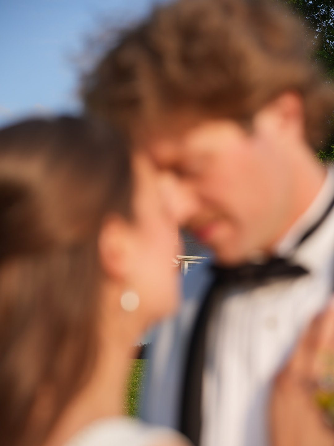 An intentionally blurred close-up of a couple's foreheads touching, soft daylight.