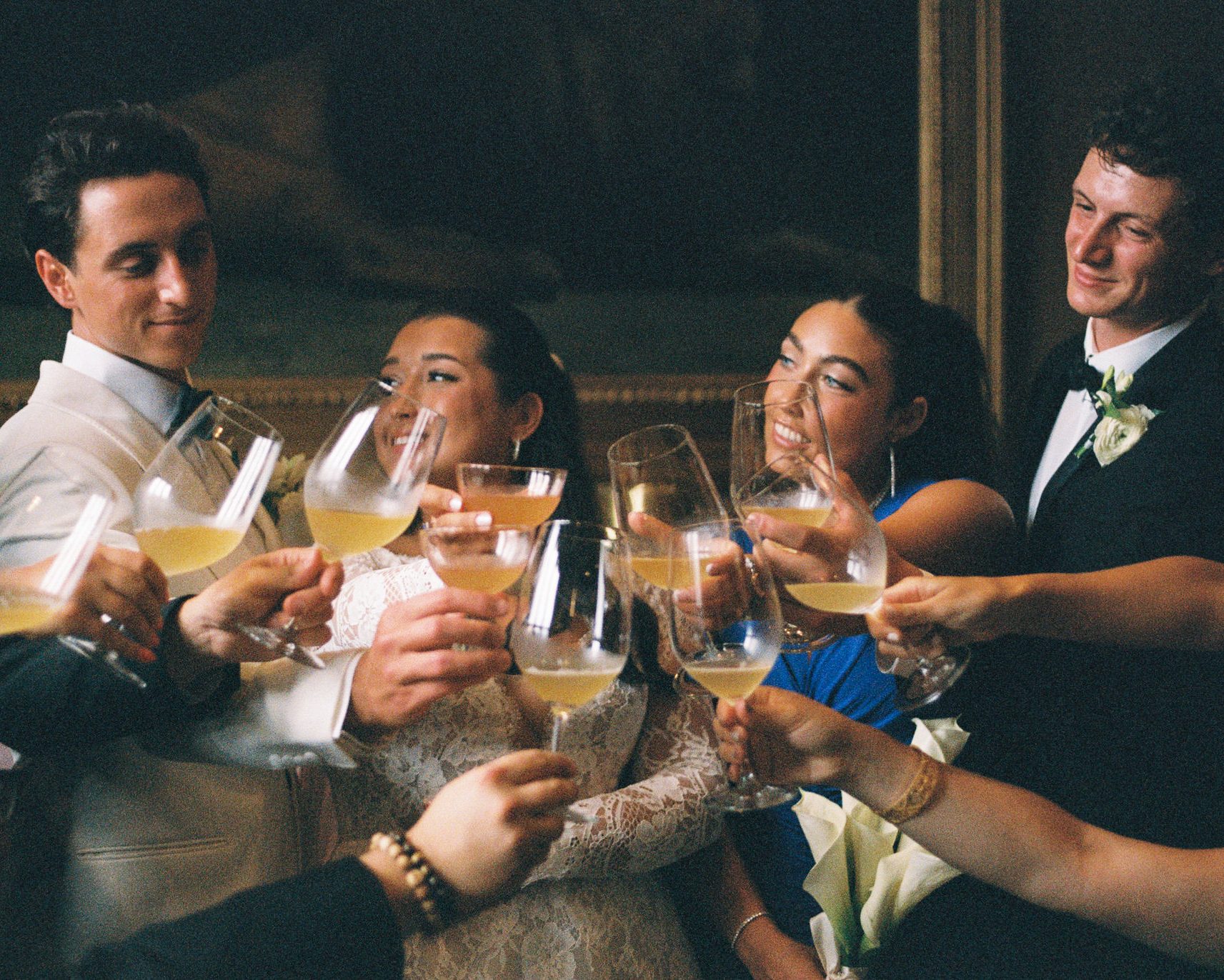 A group of wedding guests clinking glasses of champagne together in a candlelit room.